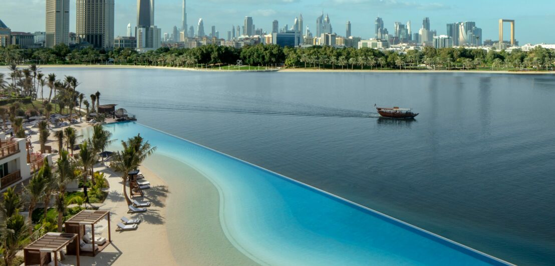 Luftaufnahme eines Hotelstrandes, im Hintergrund die Skyline von Dubai