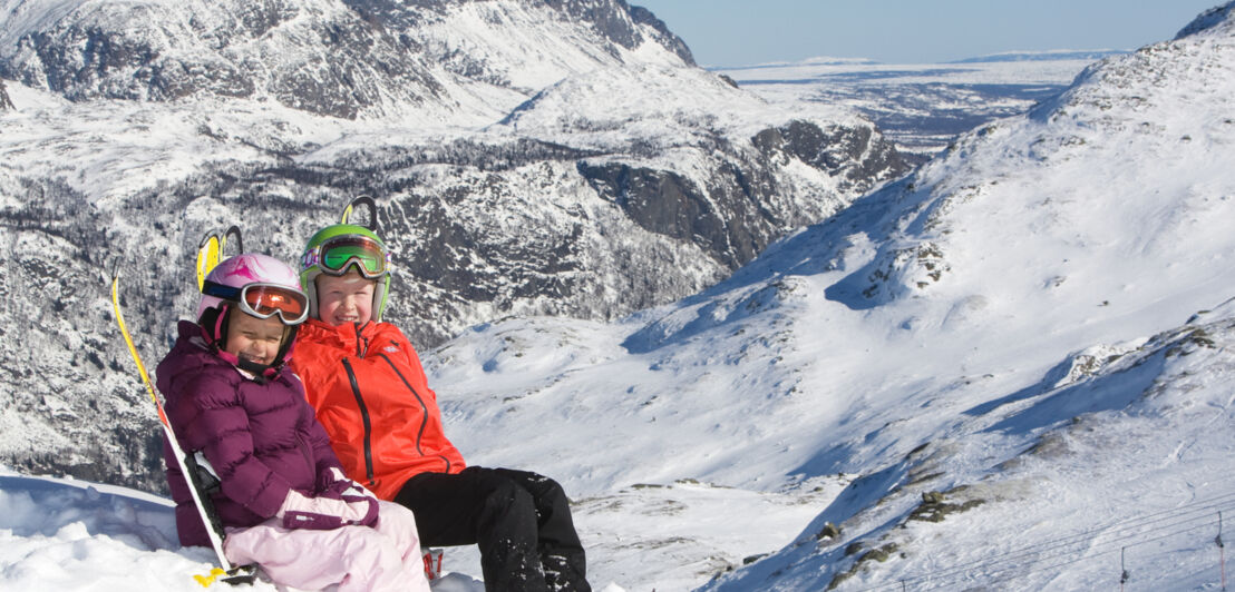 Zwei Kinder sitzen im Schnee