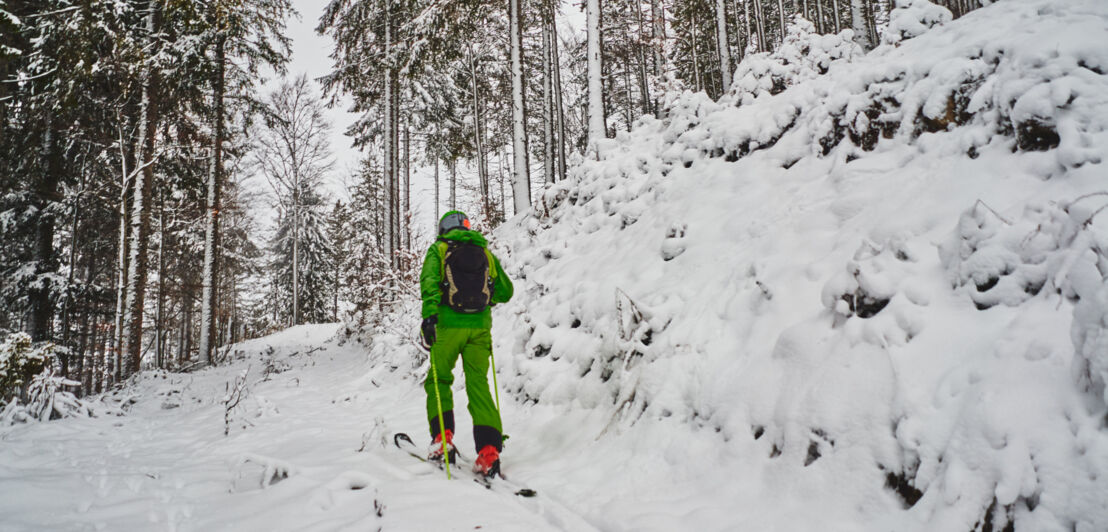 Ein Tourengeher in einem schneebedeckten Bergwald