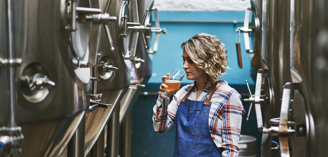 Eine Frau bei einer Bierprobe zwischen Zapffässern