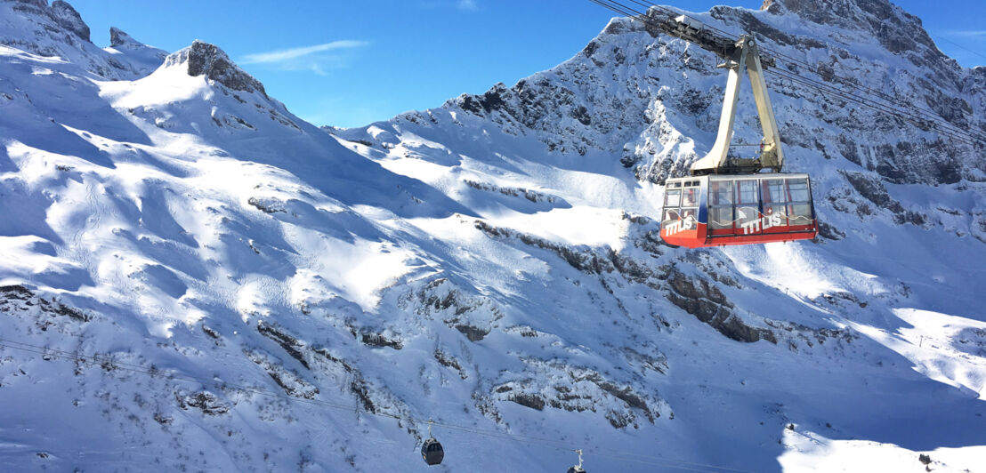 Eine große Gondel vor verschneiten Berggipfeln