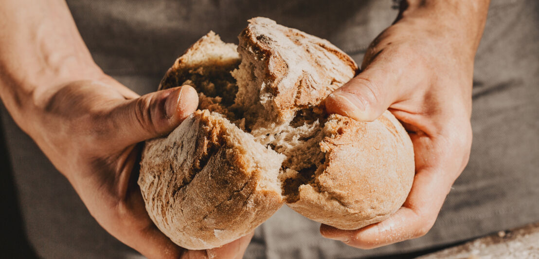 Nahaufnahme eines Brotlaibes, das in der Mitte zerbrochen wird