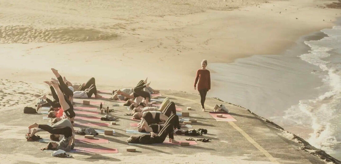 Eine Gruppe macht Yoga am Strand