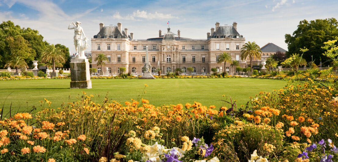 Bunte Blumen und eine Grasfläche vor dem Palais du Luxembourg.