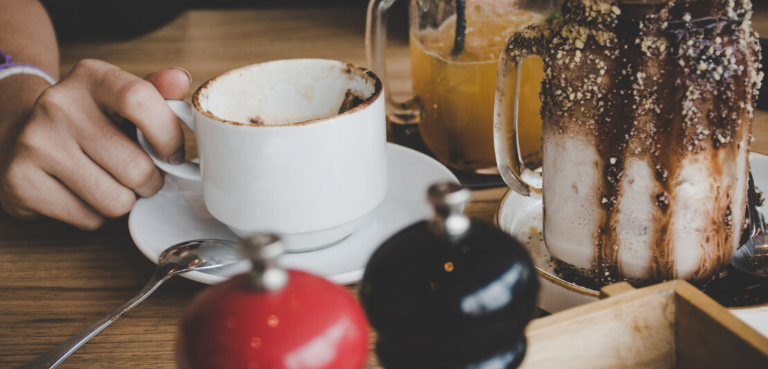 Eine Tasse neben einem Trinkbecher mit Schokoladenrand.