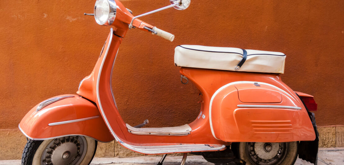 Eine orangefarbene Vespa vor orangefarbener Wand