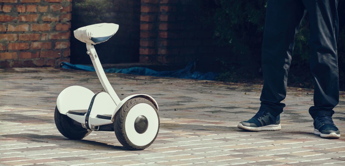 Ein junger Mann steht neben einem Hoverboard mit Sitz