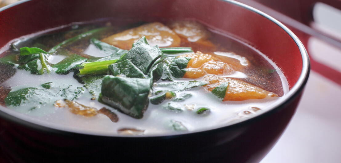 Eine Schüssel mit Misosuppe und Spinat.