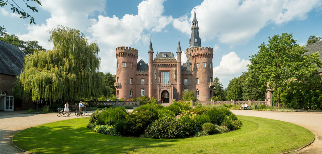 Ein neugotisches Schloss steht inmitten einer gepflegten Grünanlage