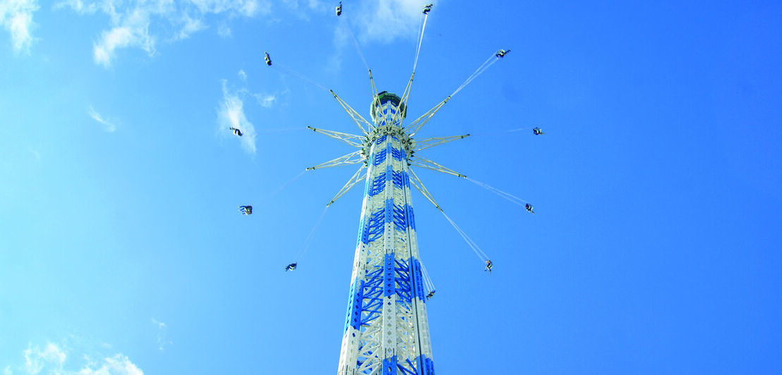 Ein blau weißes Kettenkarussell vor blauem Himmel