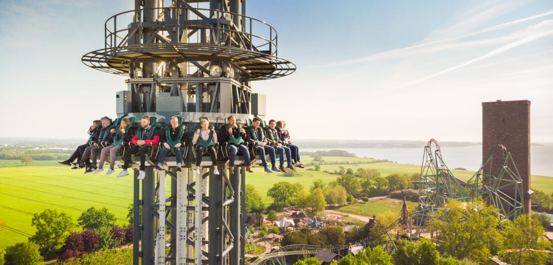 Einige Menschen hängen in Sitzen an einem Turm, bereit für den Fall