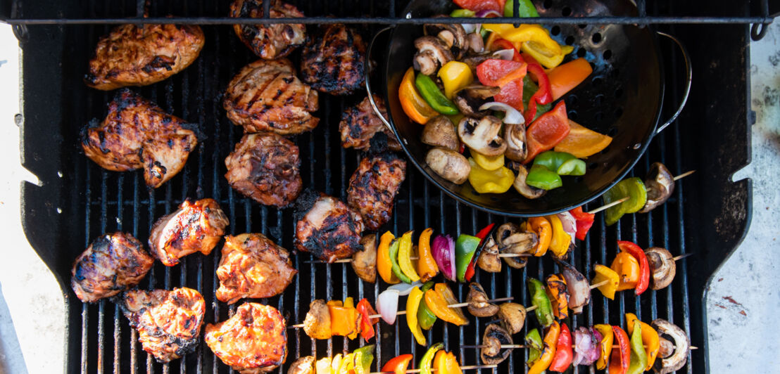 Gemüsespieße und Fleisch auf dem Rost eines Gasgrills