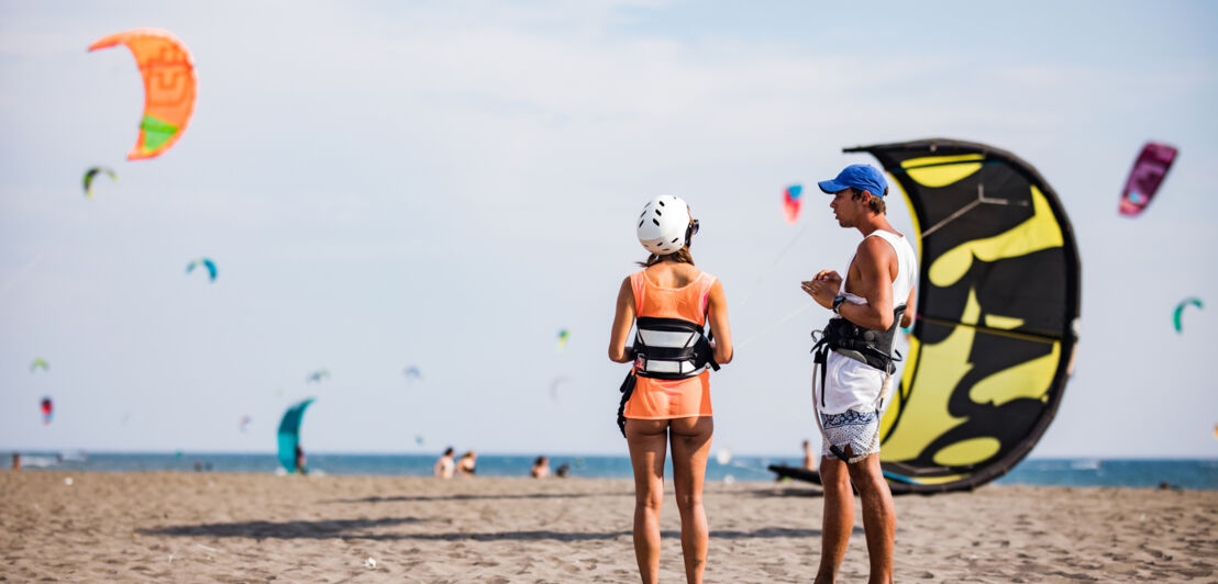 Zwei Kitesurfer:innen am Strand