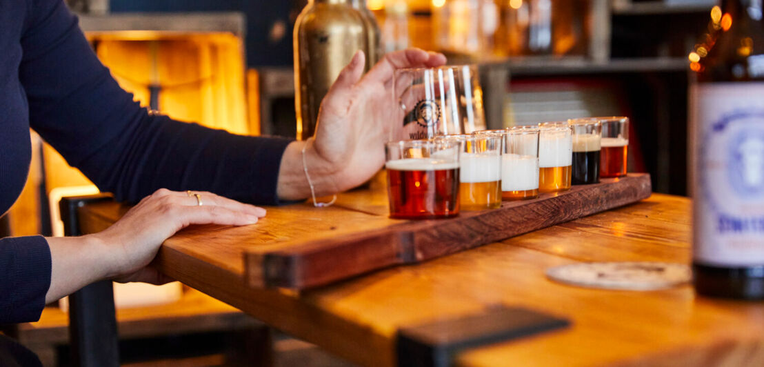 Verschiedene Biersorten auf einem Holzbrett bei einer Verkostung