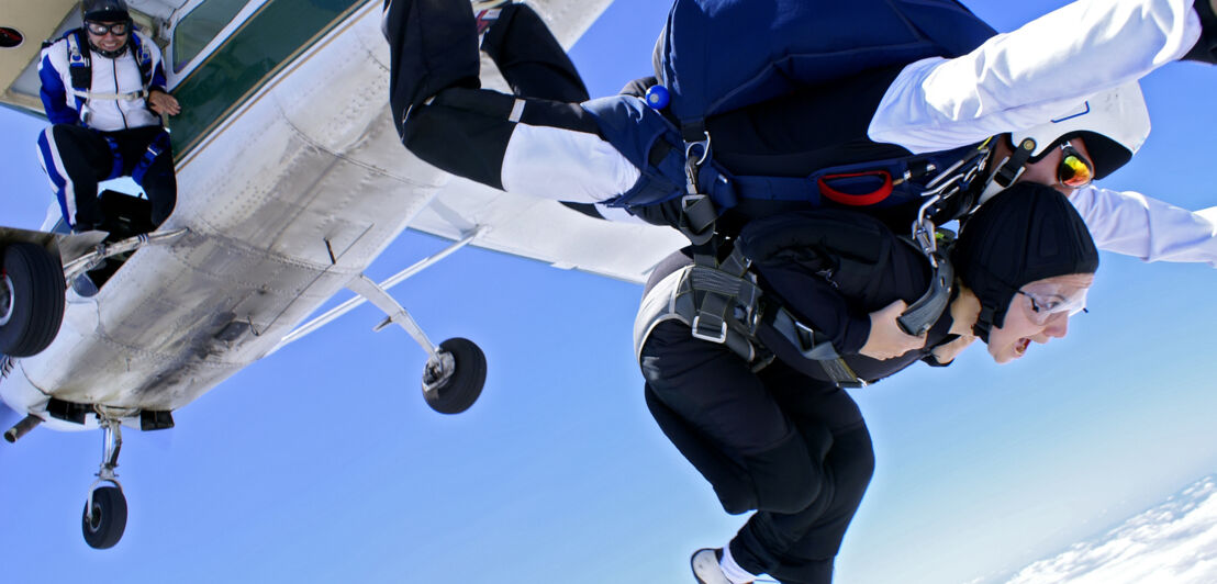 Zwei Menschen springen aus einem Flugzeug