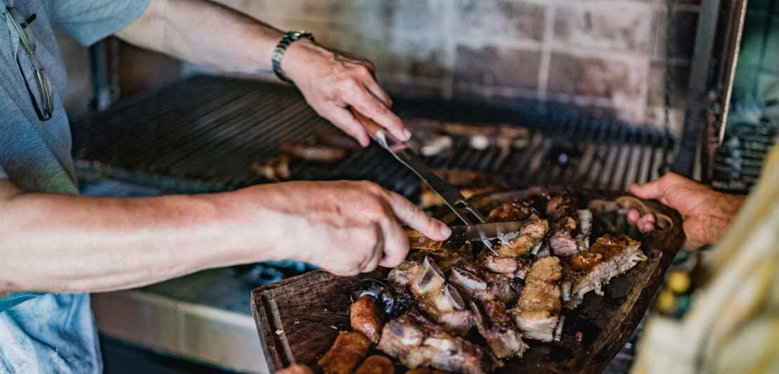 Zwei Männer, die zu Hause für die Familie Grillfleisch schneiden und servieren. 