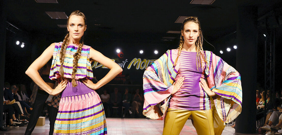 Zwei Models in gemusterten Outfits nebeneinander auf dem Runway