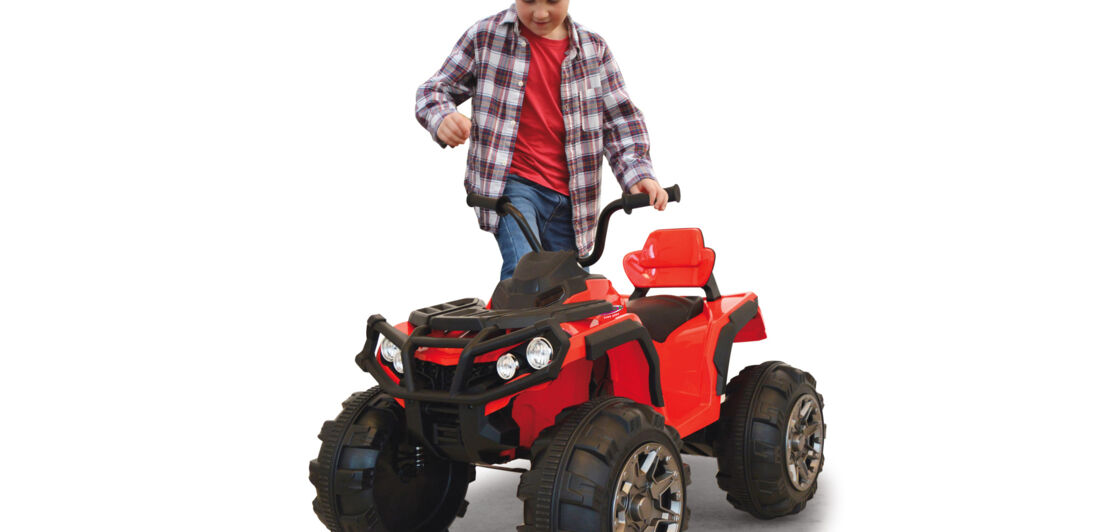 Ein kleines rotes E-Quad, auf das sich ein Junge setzen will.