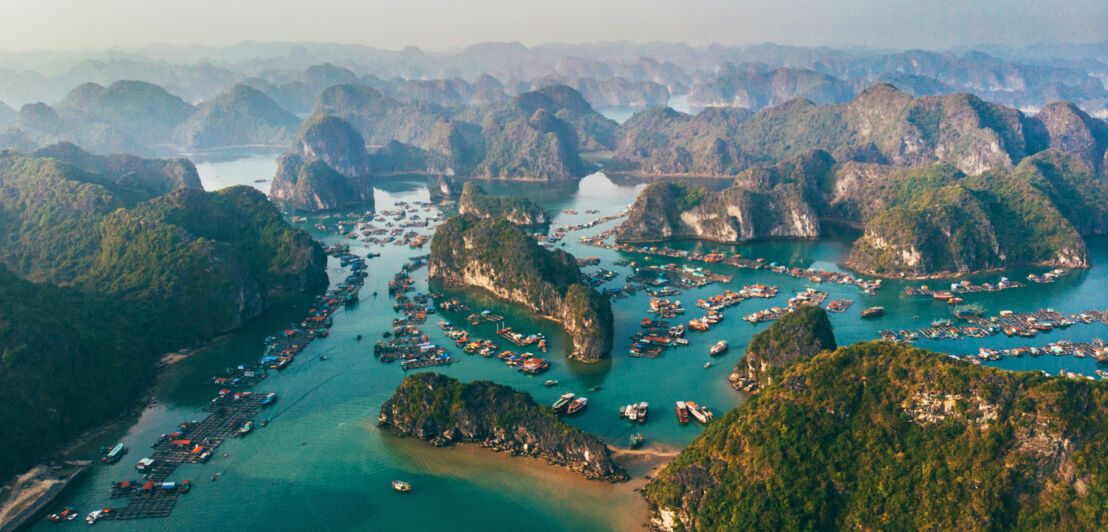 Luftaufnahme des Naturweltwunders Halong-Bucht mit Booten, die im smaragdgrünen Wassern vor zahlreichen Inseln liegen