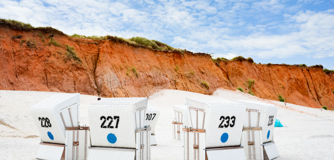 Strandkörbe auf der Insel Sylt am Strand vor roten Klippen