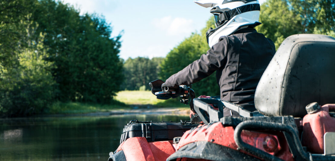 Ein Mann mit Helm und Schutzkleidung sitzt auf einem Quad an