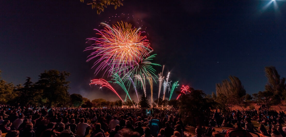 Feuerwerk über einer Ansammlung von Menschen.