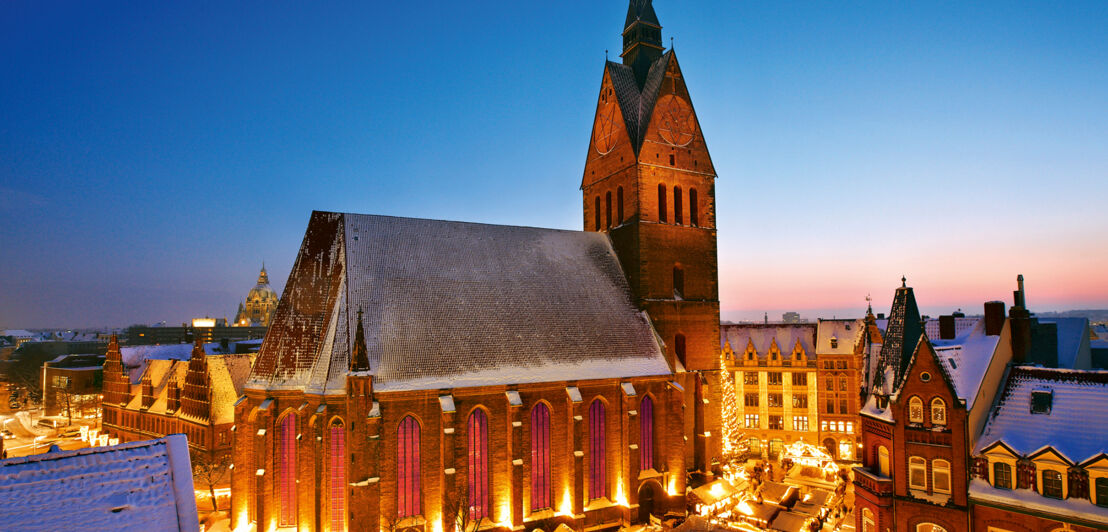 Eine Kirche in der Abenddämmerung, um die sich mehrere beleuchtete Stände gruppieren