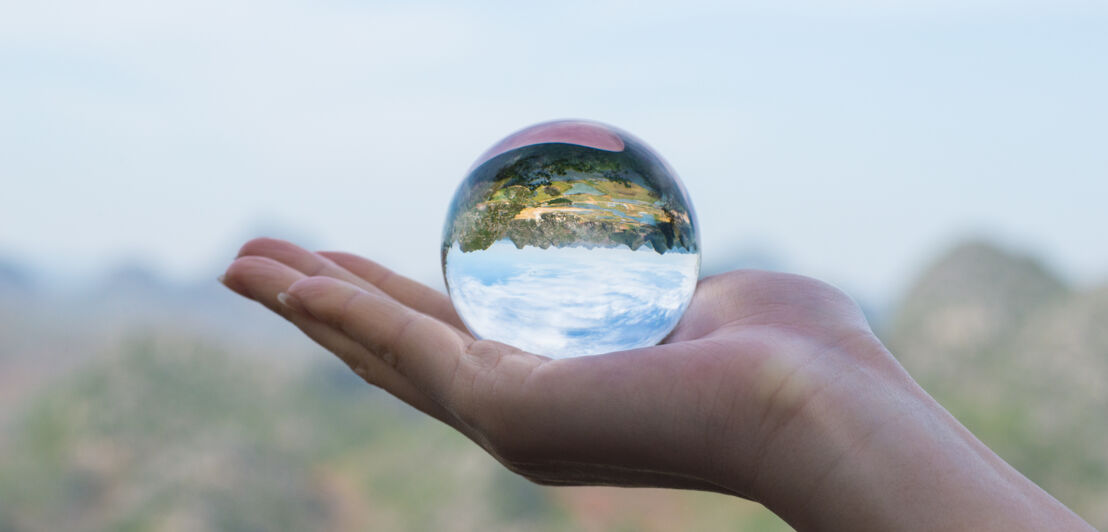 Eine Hand hält eine Glaskugel in der Hand