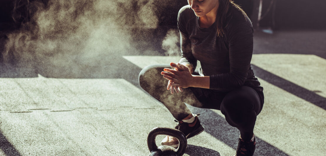 Eine Frau, die neben einem Kettle Bell hockt