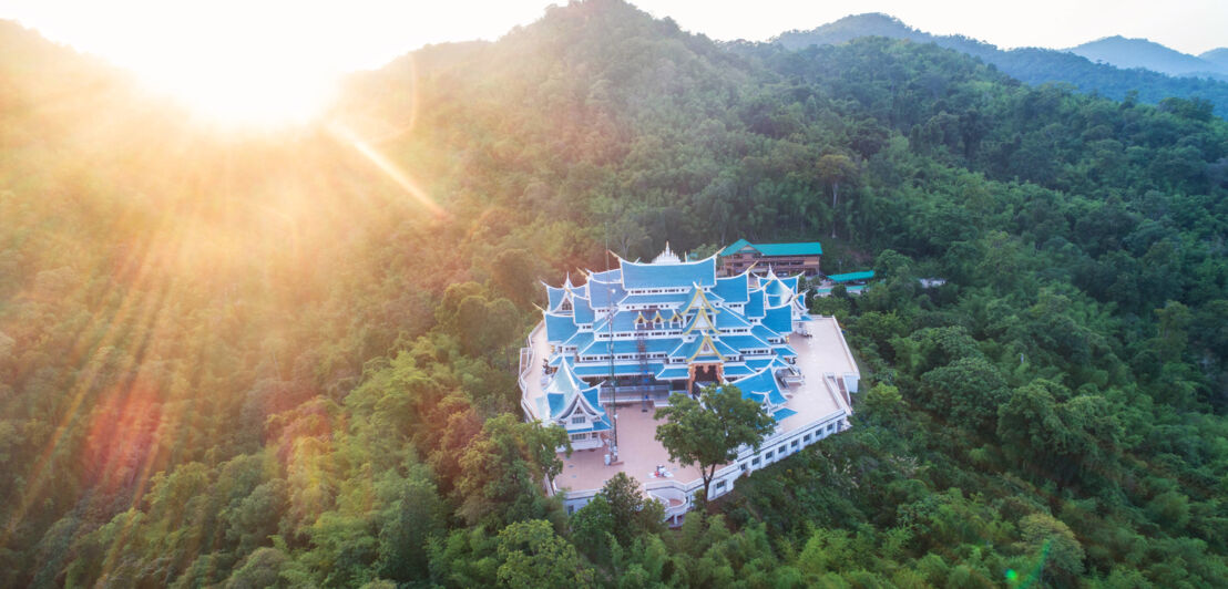 Tempel mit blauen Dächern auf einem Berg, umgeben von Urwald