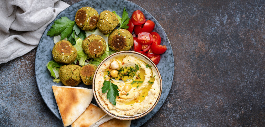 Teller mit Brot, Tomaten und einer Schale mit Hummus