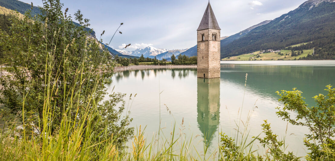 Der Kirchturm im Reschensee mit Bergen im Hintergrund