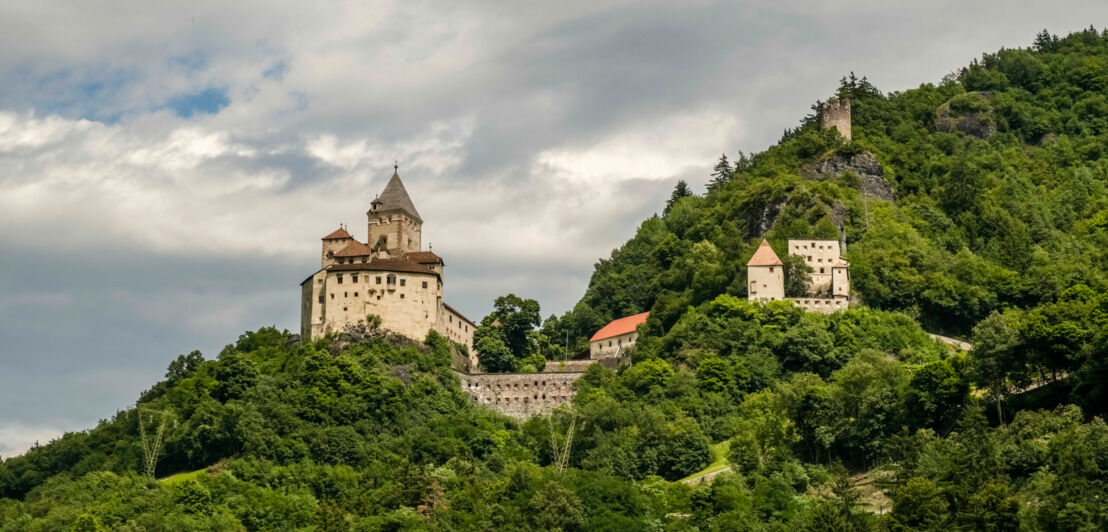 Das Schloss von Bergsteiger Reinhold Messner, das mitten im Grünen auf einem Berg steht. 