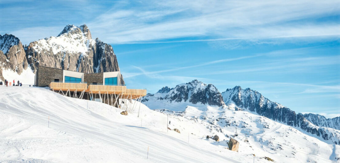 Blick auf das Restaurant The Japanese by The Chedi Andermatt, das mitten im Schnee an einem Berghang liegt