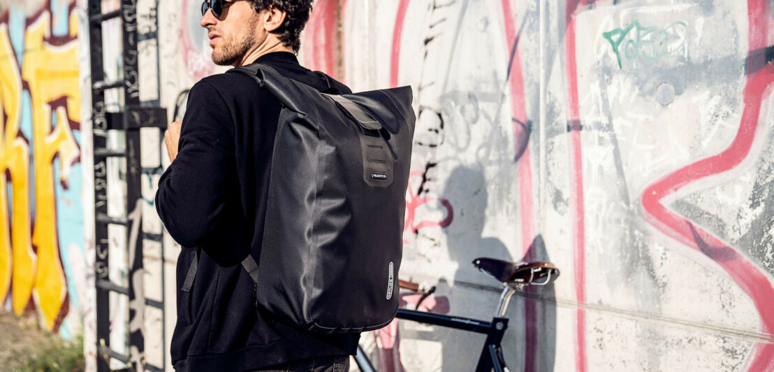 Mann mit Fahrrad und Laptop-Rucksack Velocity