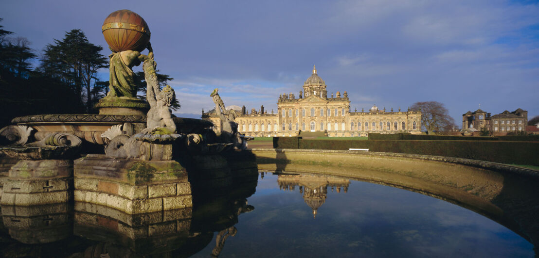 Außenansicht von Castle Howard mit Springbrunnen im Vordergrund bei Abenddämmerung.