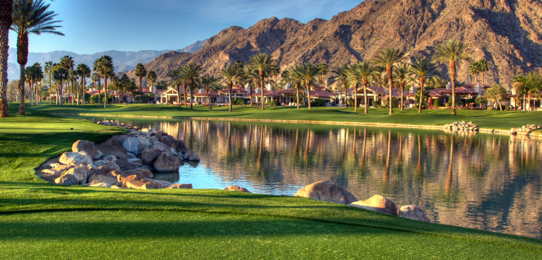 Ein See mit Palmen und Bergkulisse in der Stadt Palm Springs in Kalifornien.