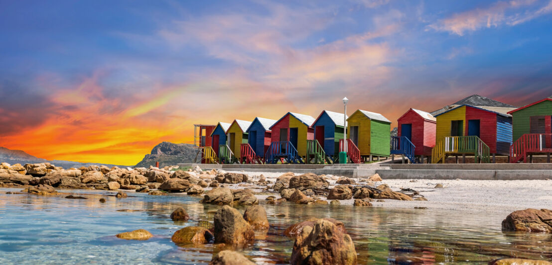 Bunte Holzhäuschen am Strand bei Sonnenuntergang