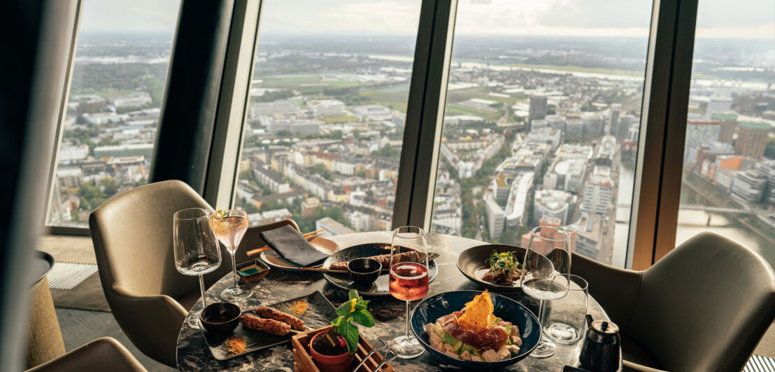 Ein gedeckter Marmortisch im Qomo vor Panoramafenstern mit Blick auf Düsseldorf