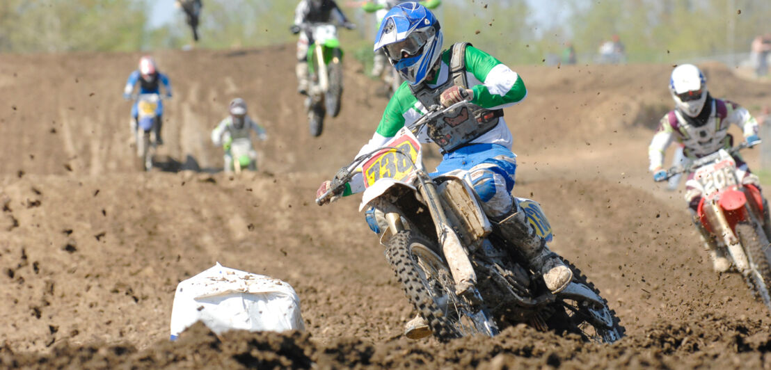 Auf einer erdigen Motocross-Strecke vom MSC Grevenbroich sind mehrere Fahrer zu sehen