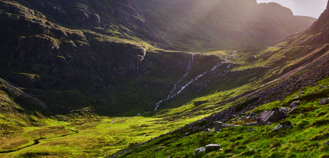 Blick auf grüne Berge, darüber bewölkter Himmel