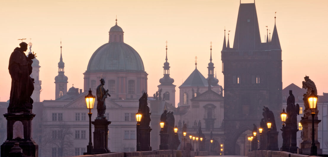 Karlsbrücke mit steinernen Statuen vor Stadtpanorama von Prag