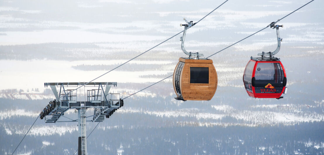 Seilbahn mit hölzerner Gondel mit Sauna vor Schneelandschaft