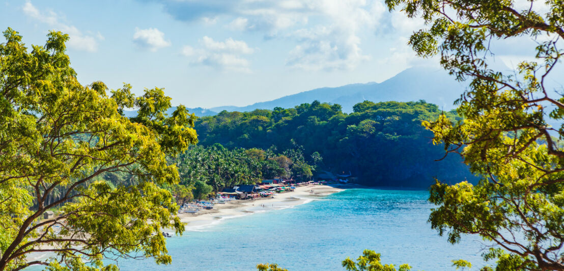 Aufsicht auf eine kleine Bucht mit Sandstrand, umgeben von Dschungel