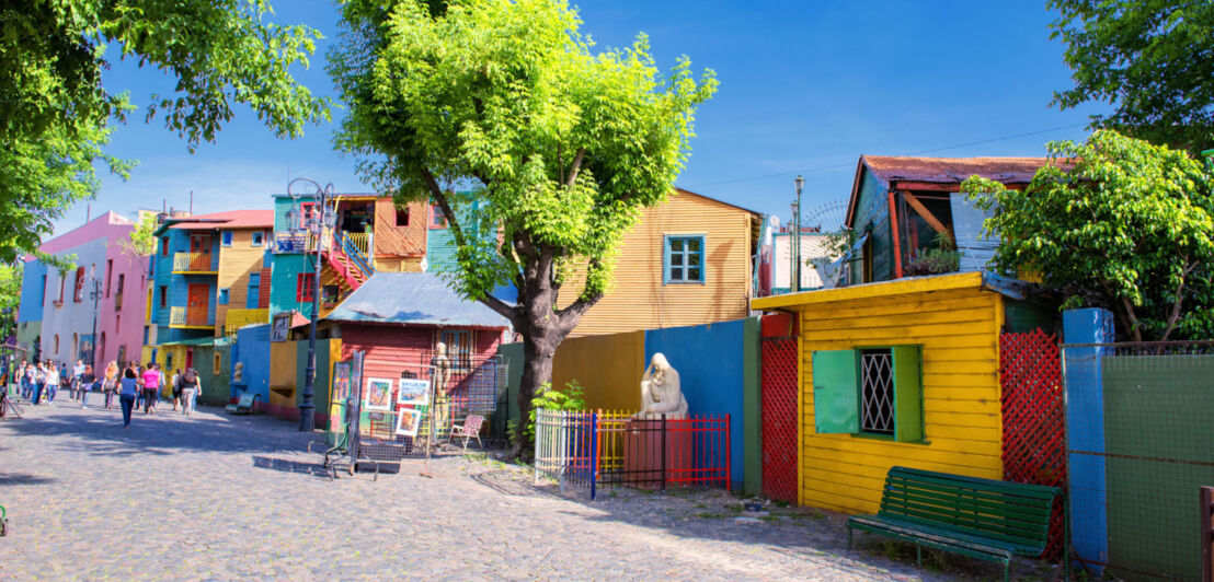 Bunte Wellblechhäuser entlang einer Fußgängerstraße mit Kopfsteinpflaster