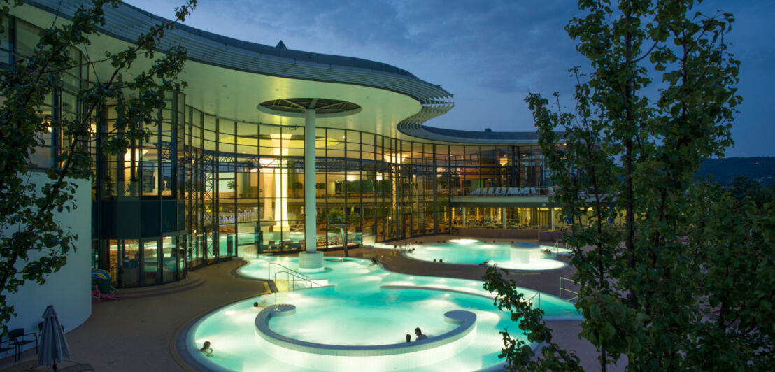 Beleuchtete Außenbecken einer Therme am Abend