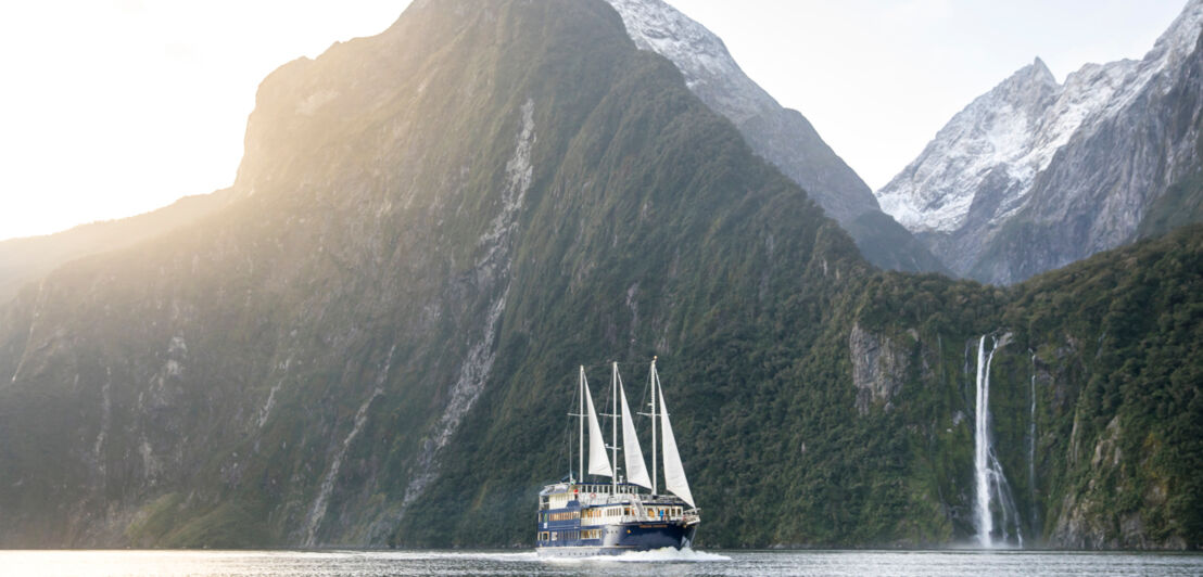 Ein Segelboot vor den Klippen von Milford Sounds