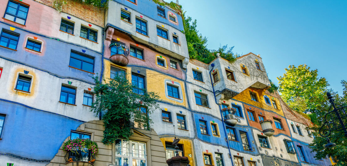 Außenansicht eines Hundertwasserhauses mit bunter und begrünter Fassade