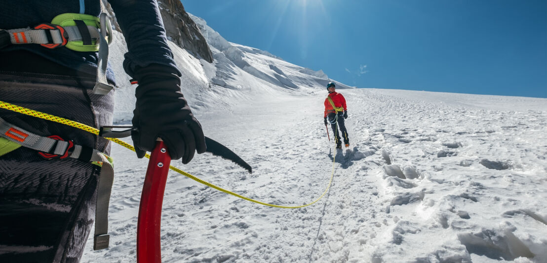 Zwei Personen mit Kletterausrüstung an einem schneebedeckten Berg