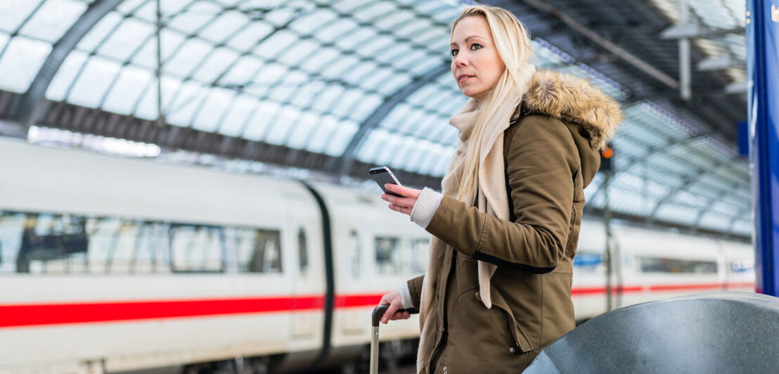 Woman in train station using time table app on phone